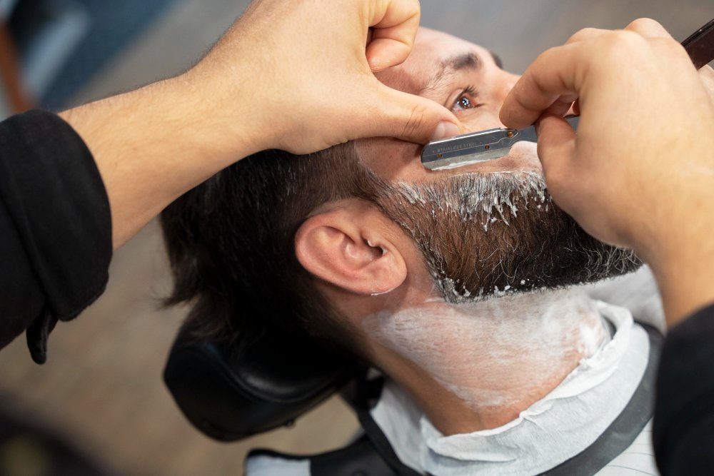 Barber expertly shaving clients face with a straight razor